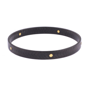 Angled view of Carbon Bangle with Large 18k Yellow Gold Rivets by Diana Hall