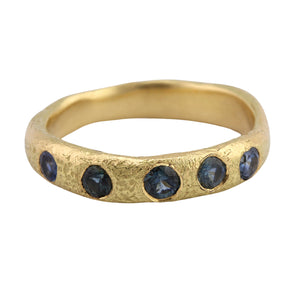 Angled view of Narrow Molten Band in 18k yellow gold with blue-green sapphires by Betsy Barron