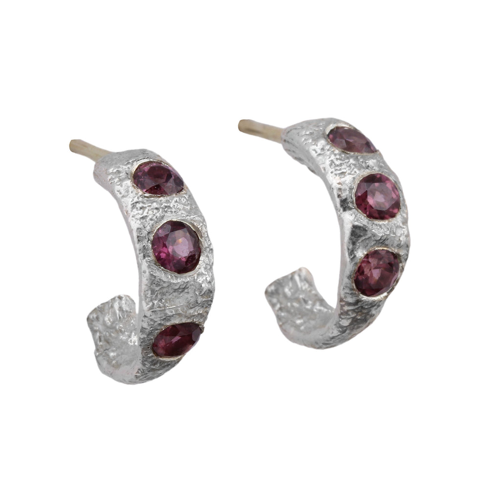 Angled view of Small Molten Hoop earrings in sterling silver with rhodolite garnets by Betsy Barron Jewellery