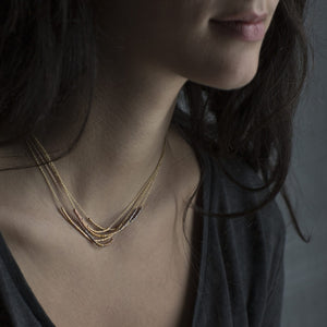 Detail view of model wearing several Tiny Bead Color Graded Necklaces by Sia Taylor.