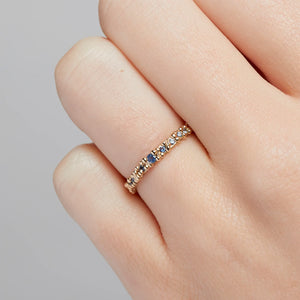 Detail view of model wearing Blue Sapphire Granule Eternity Band by Ruth Tomlinson on left ring finger.