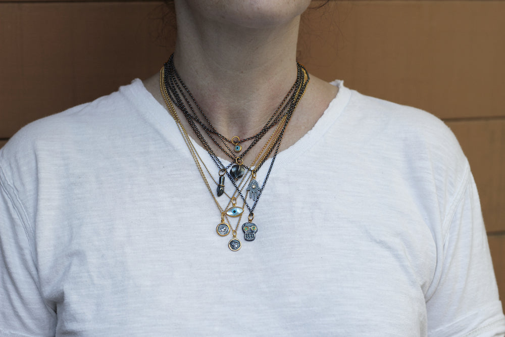 Model wearing several layered necklaces by Prehistoric Works