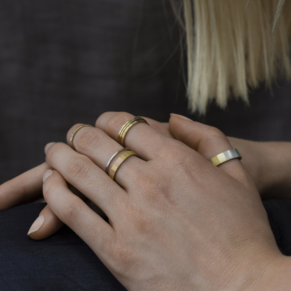 Closeup of several Sia Taylor rings on model's hand.