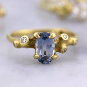 Blue Sapphire Cluster Ring by Johnny Ninos, with other blurred rings in background.