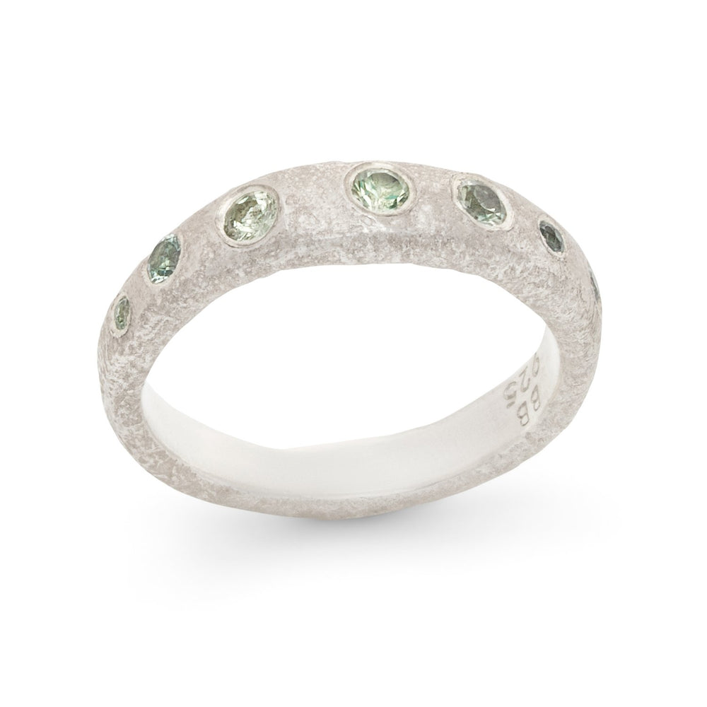 Angled view of Narrow Molten Band in Sterling Silver with green sapphires by Betsy Barron