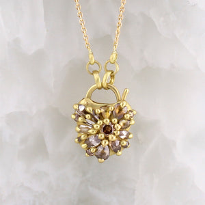 Petite Coeur de Fantaisie Necklace by Polly Wales hanging in front of quartz display